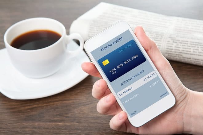 Smartphone mit Mobile Wallet neben einer Kaffeetasse
